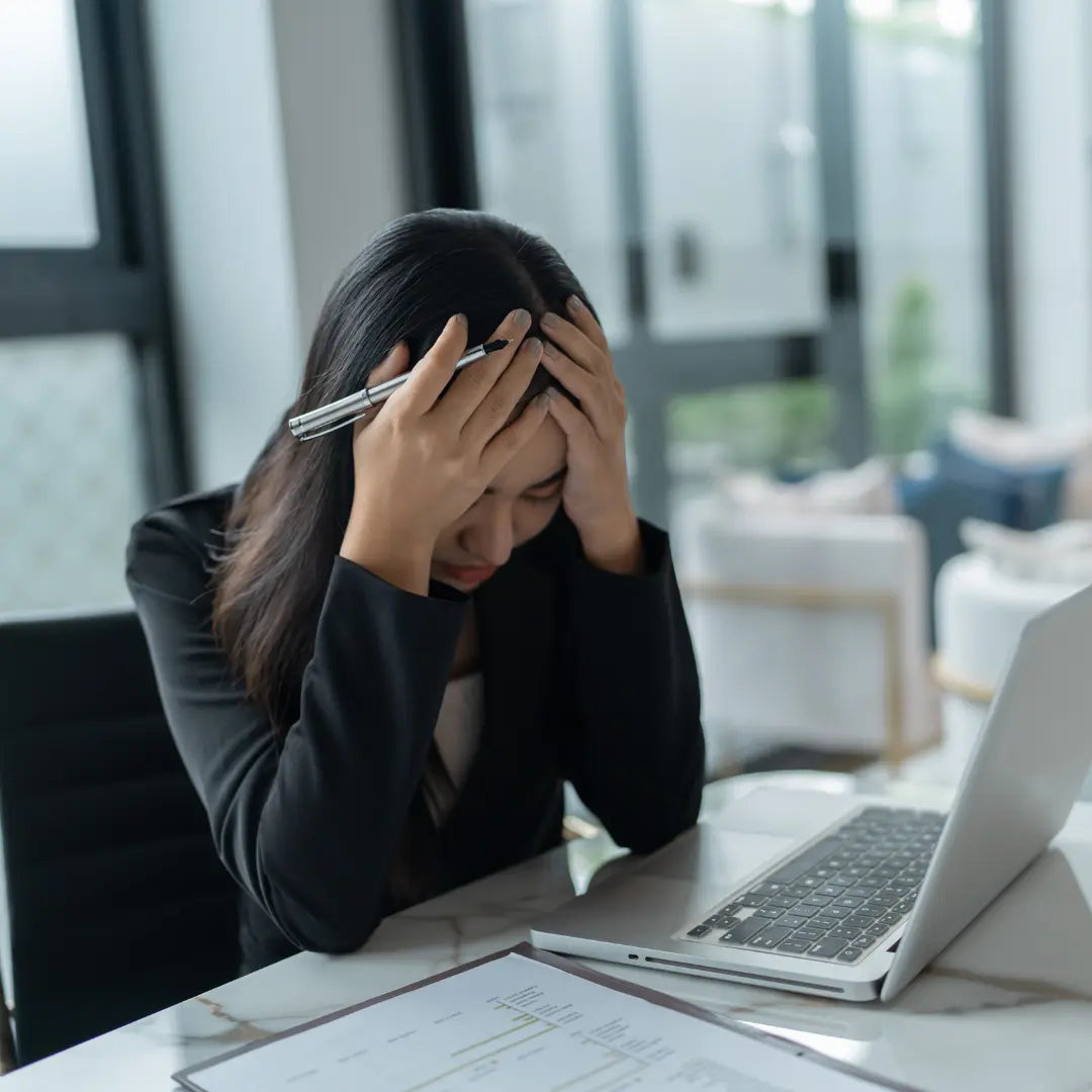Donna alla scrivania con la testa stressata tra le mani