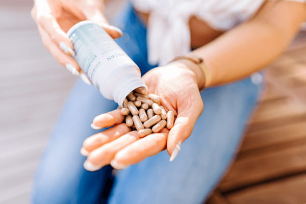 person holding bottle with capsules