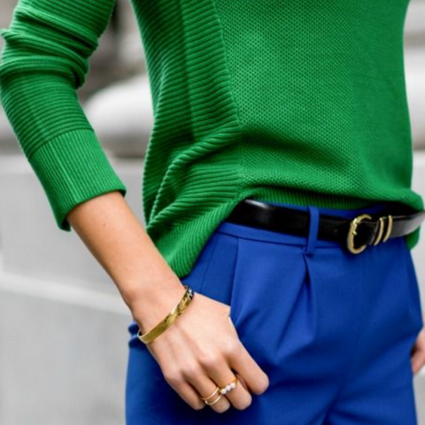 Lady wearing blue trousers with a black belt and green sweater