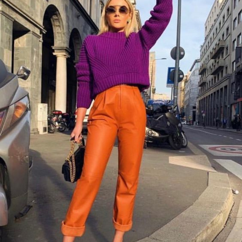 Lady wearing leather orange trousers with a purple knitted sweater