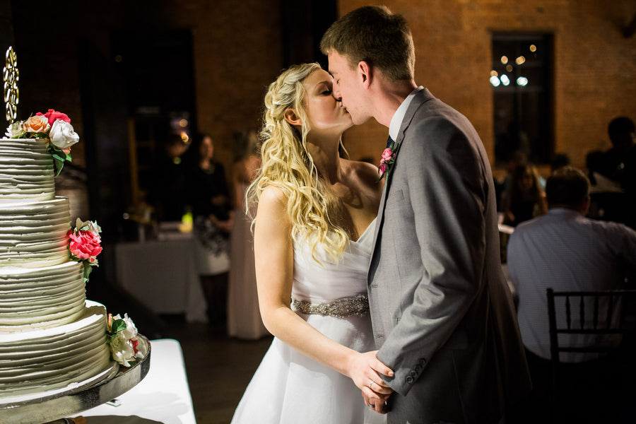 Bride and Groom Kissing by Cake | Asteria Photography | Floral Inspired Wedding