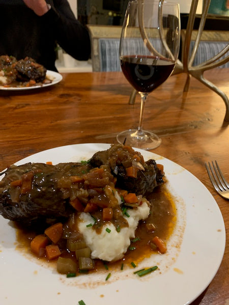 Red Wine Braised Short Ribs Served over fluffy mashed potatoes garnished with chives and enjoyed with a glass of red wine