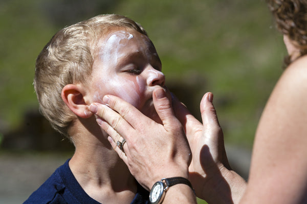 Mother applying sunscreen to boy