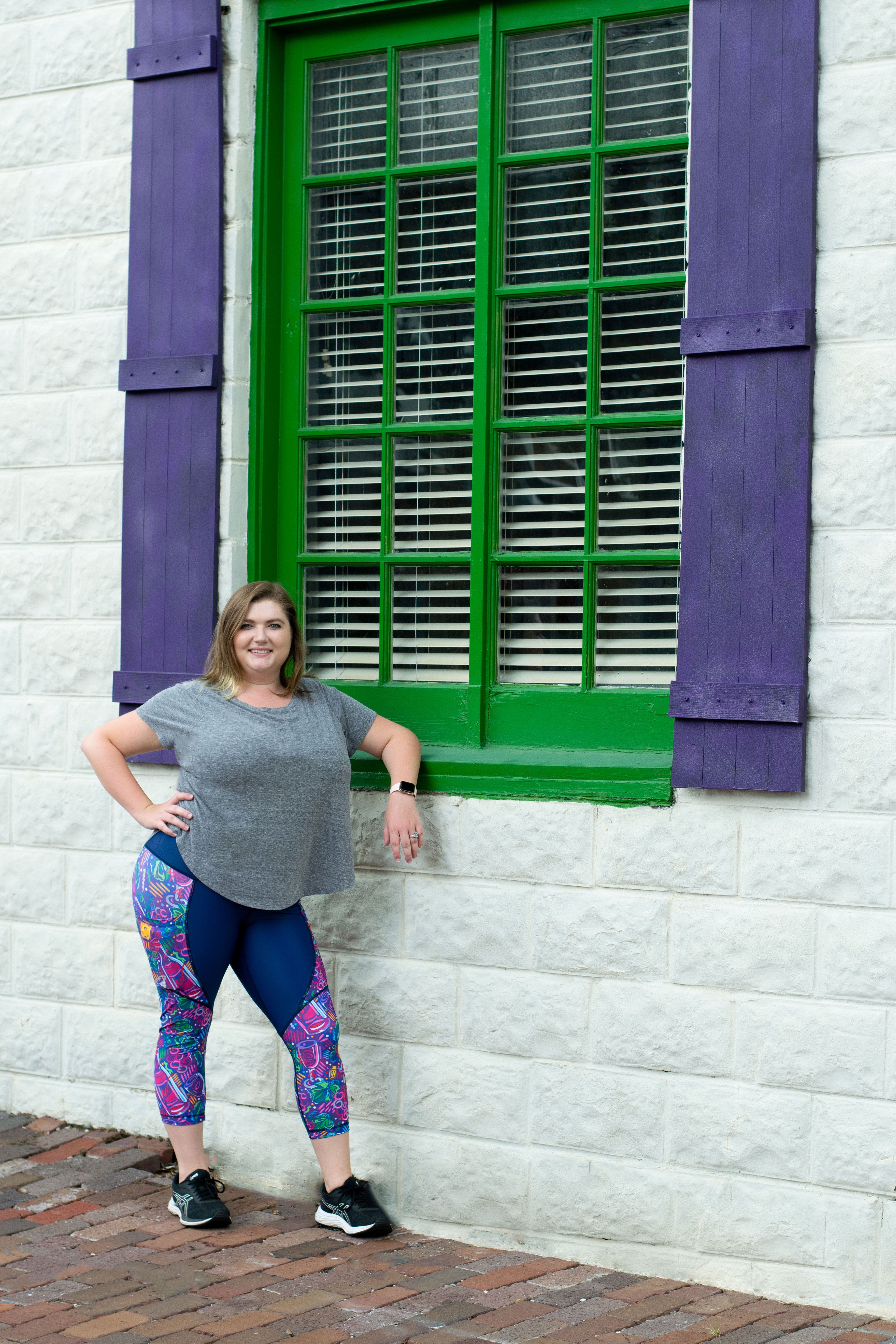 Model leaning against colored window wearing Wine Me Up capris