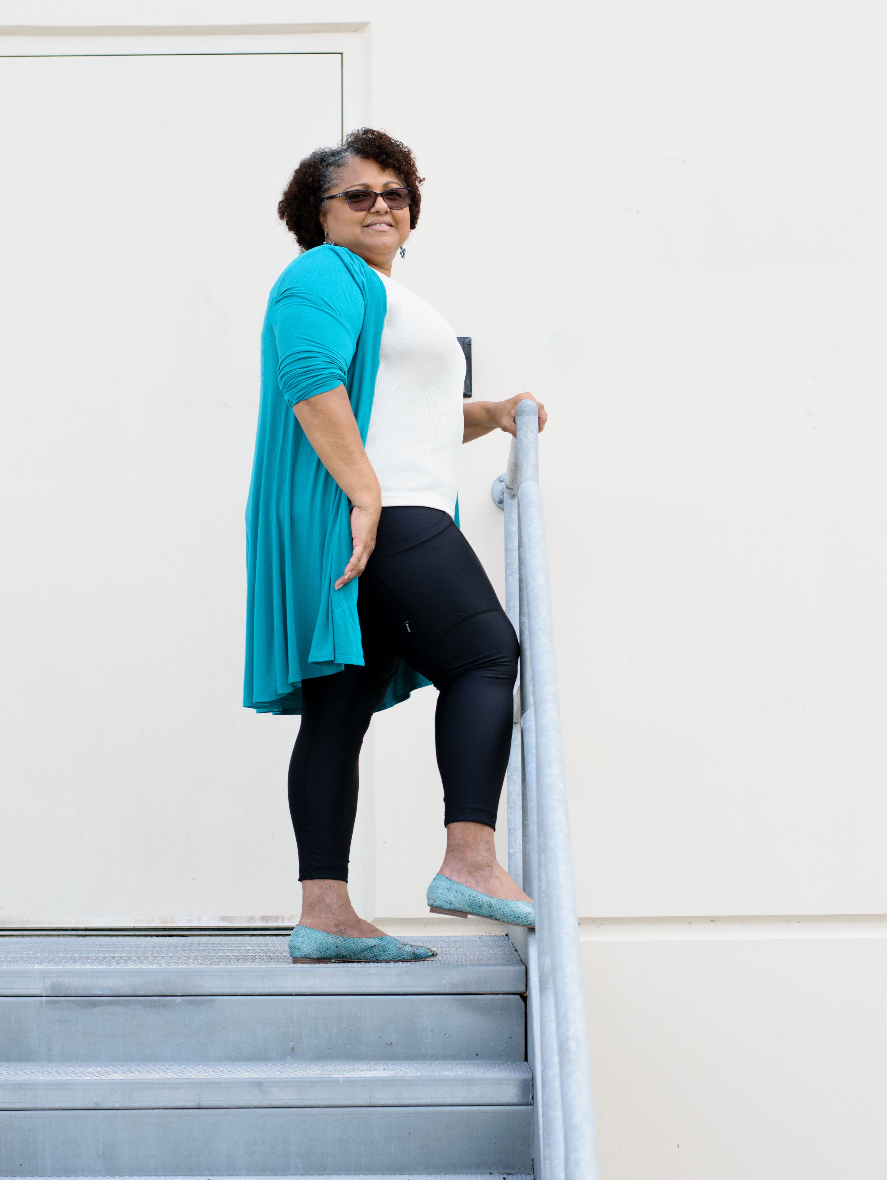 Model with foot on railing wearing black capris