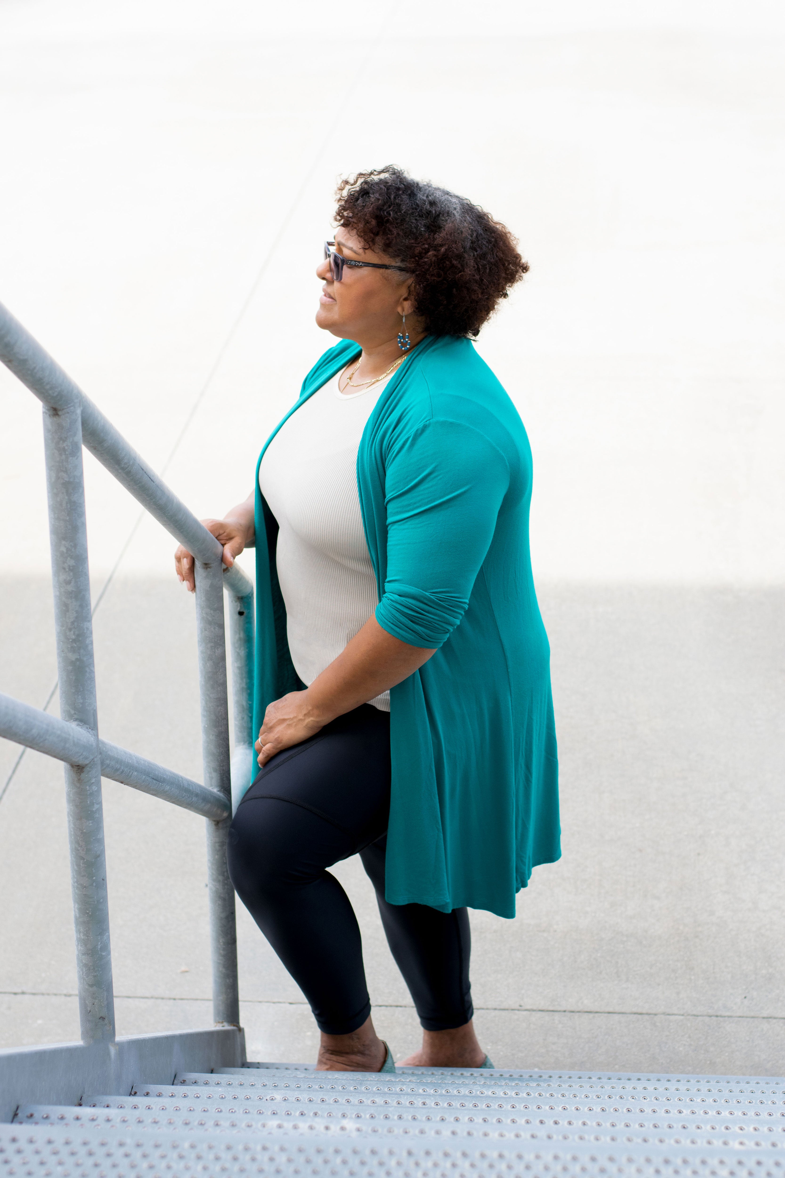 Model holding railing wearing black capris