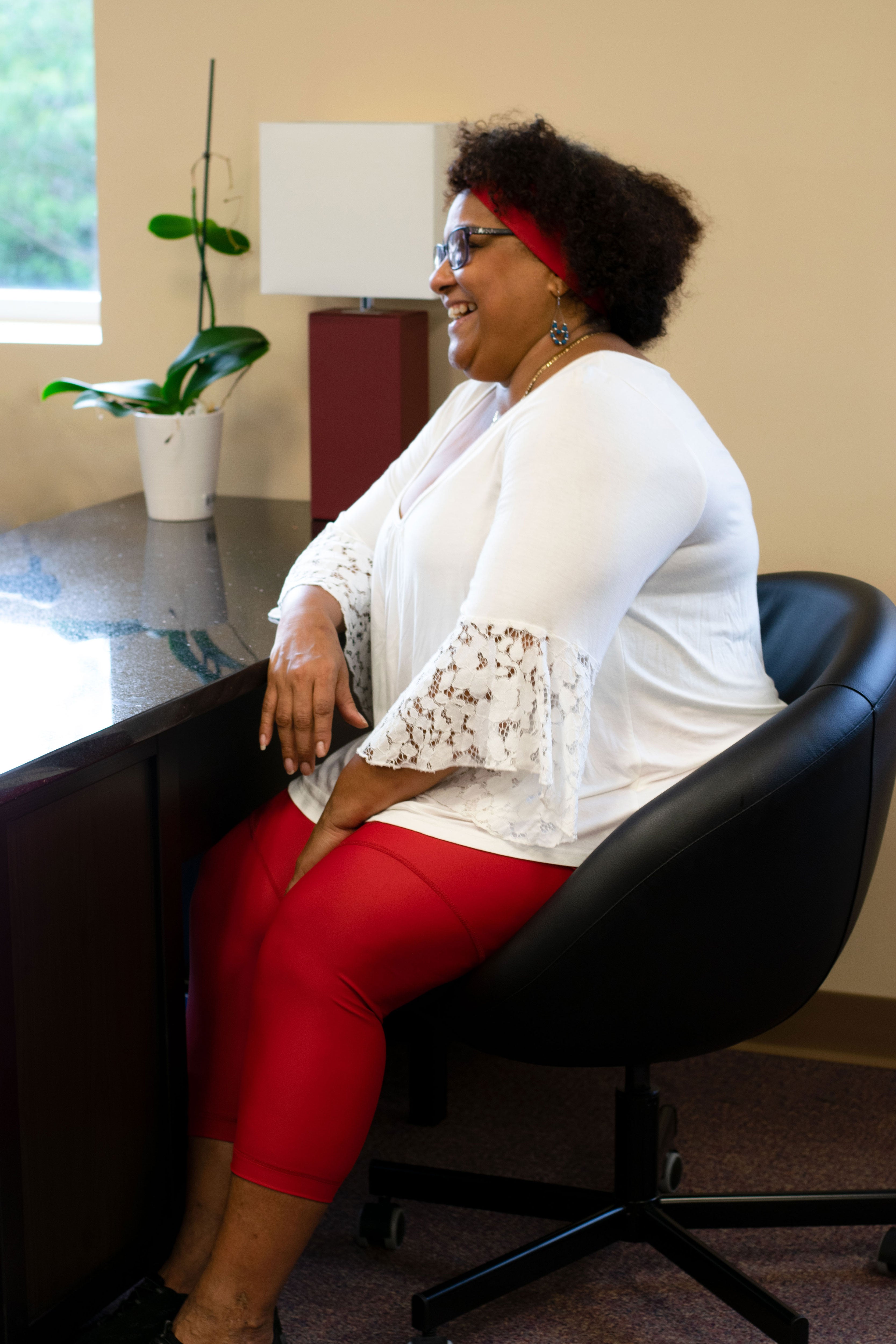 Model sitting in chair wearing red capris