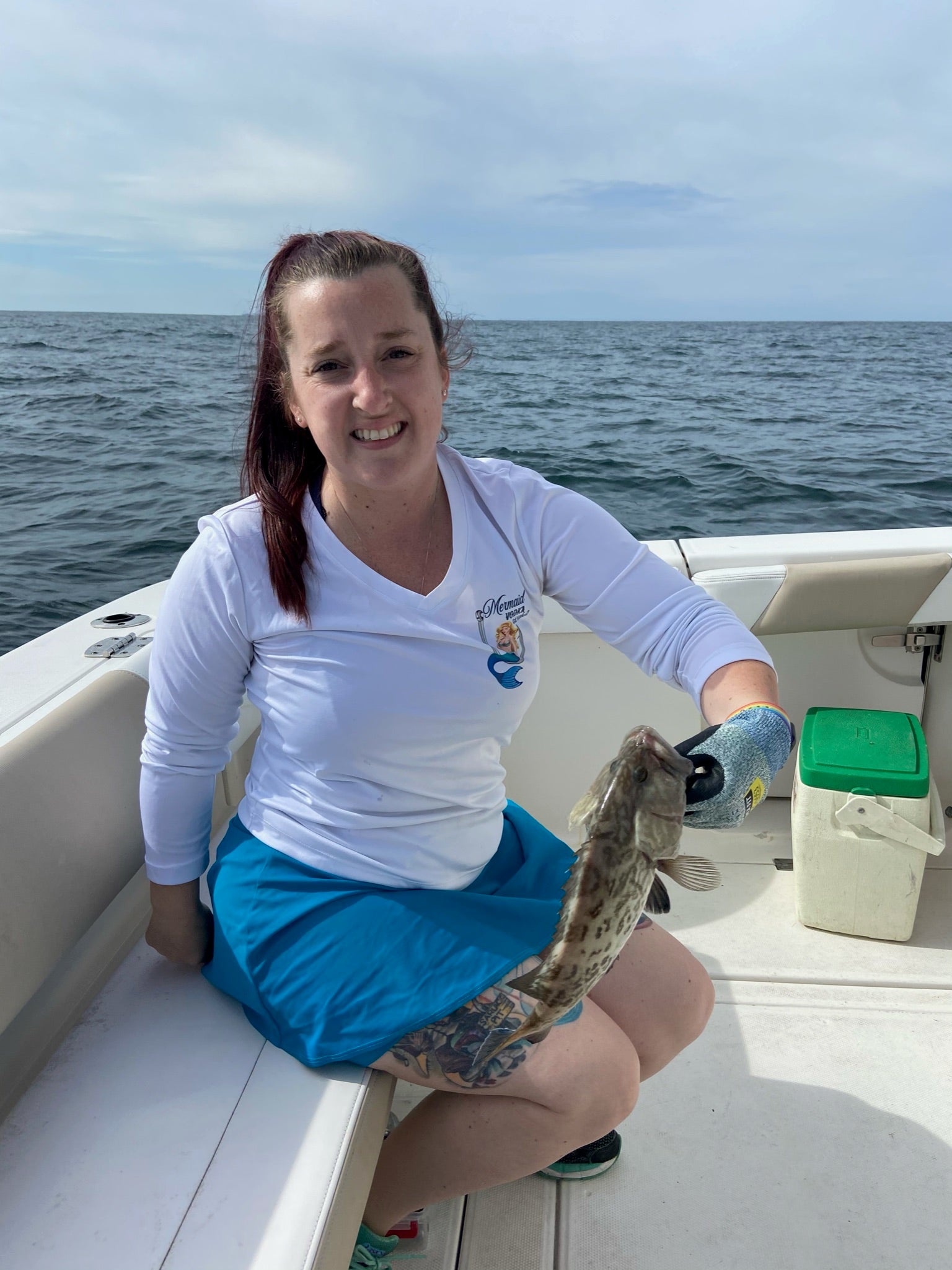 Becky on a boat holding a fish while wearing a Bolder skirt
