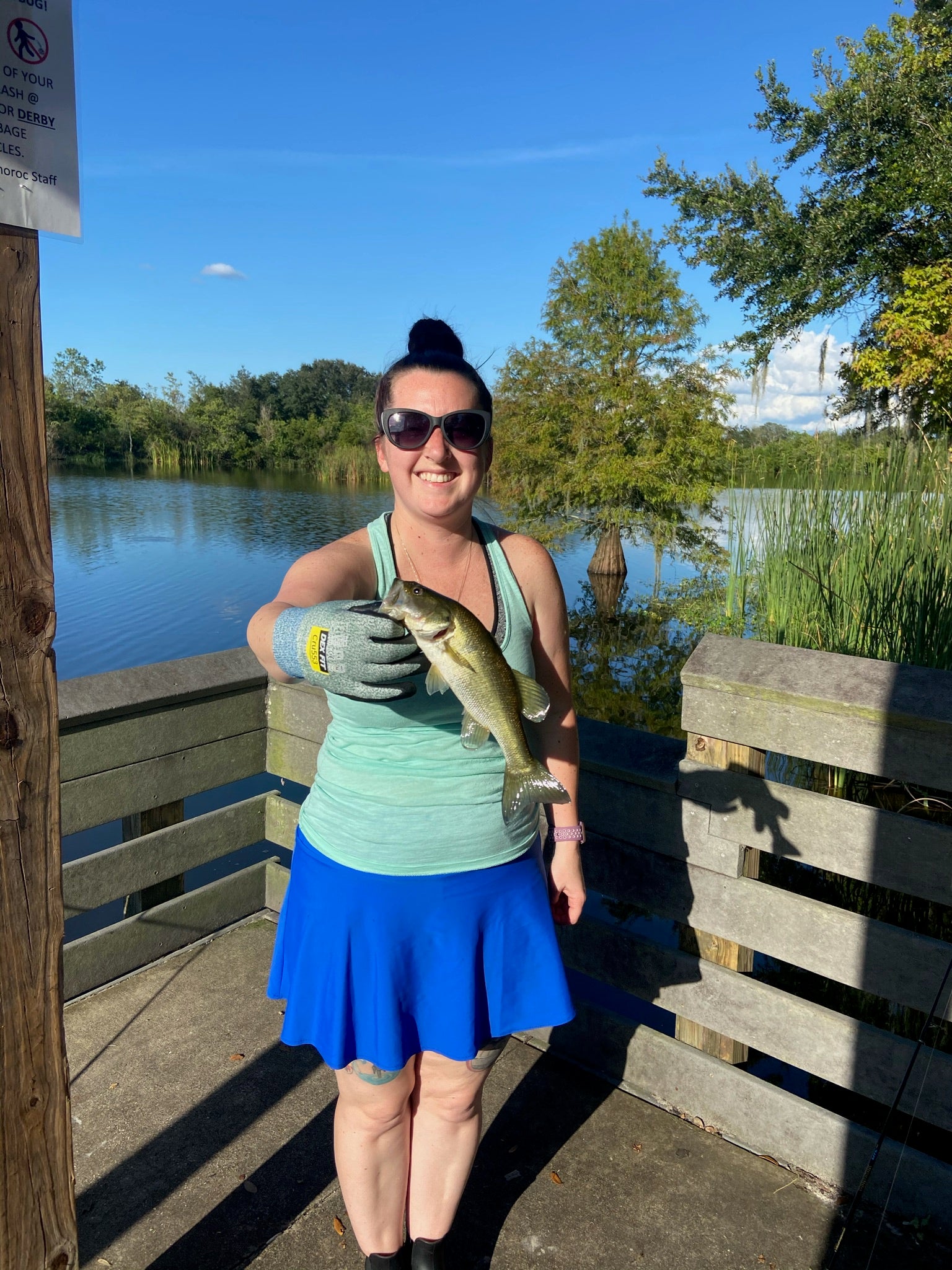 Becky on a dock holding a fish while wearing a Bolder skirt