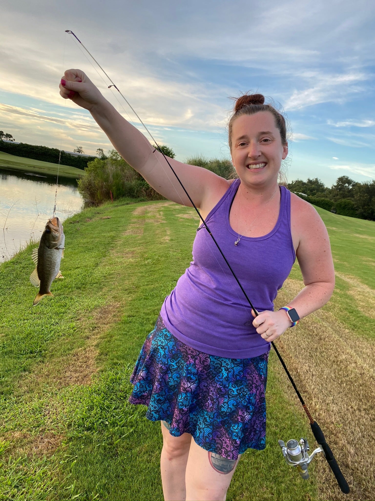 Becky holding a fish on a line while wearing a Bolder skirt