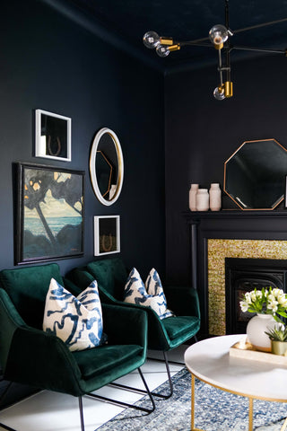 Green velvet chairs overlooking a brass and marble centre table in a moody living room