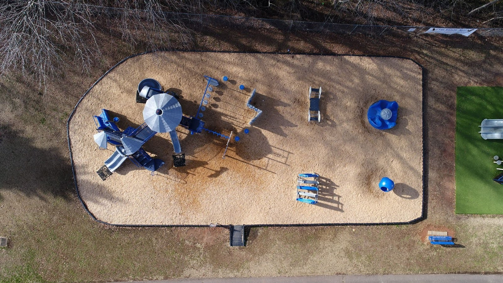 Aerial view of outdoor children’s playground with slides and swings on a sandy surface
