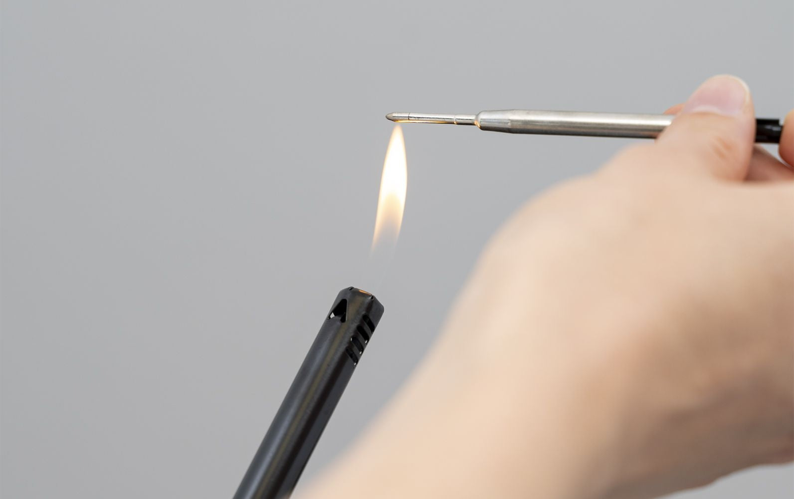 ballpoint refill tip held over lighter flame