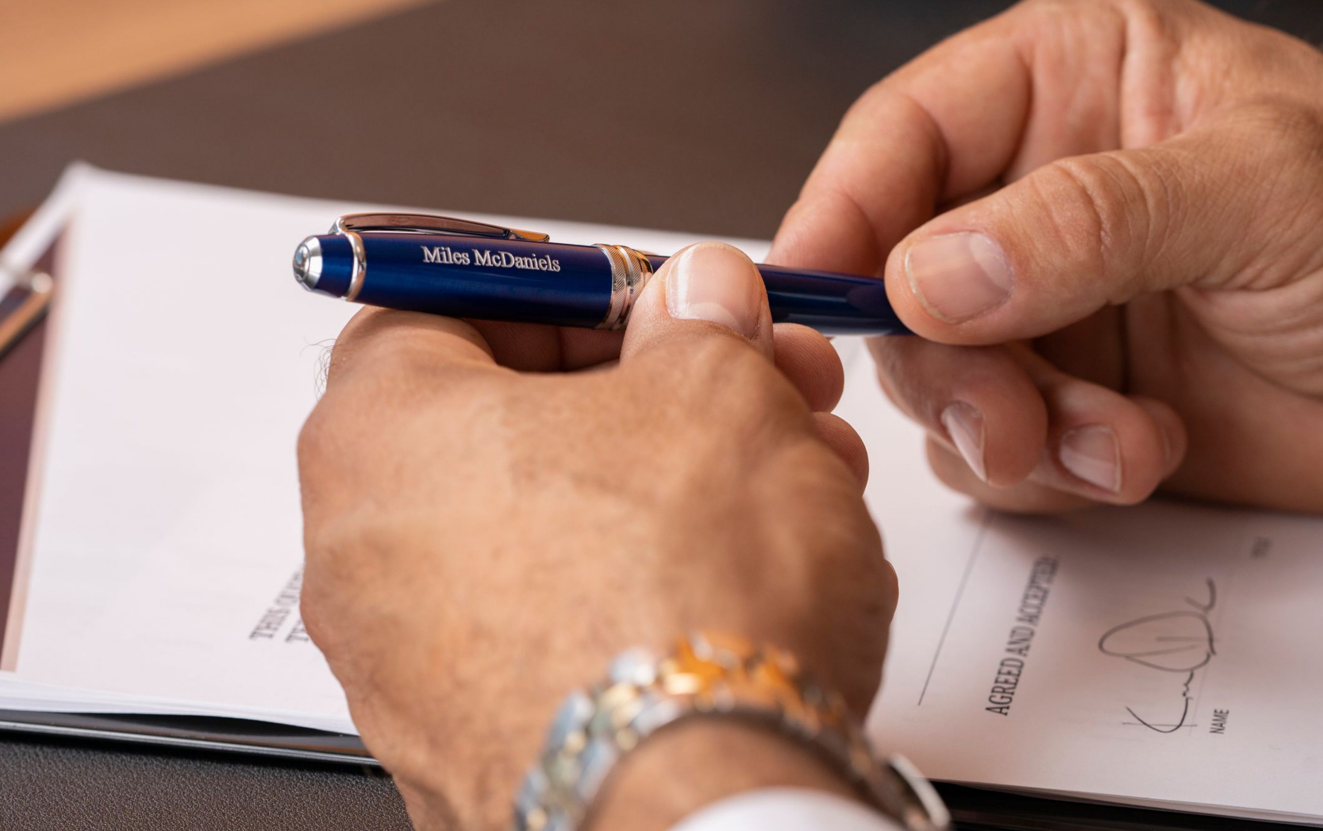 Man holding engraved Bailey Blue Ballpoint to sign document