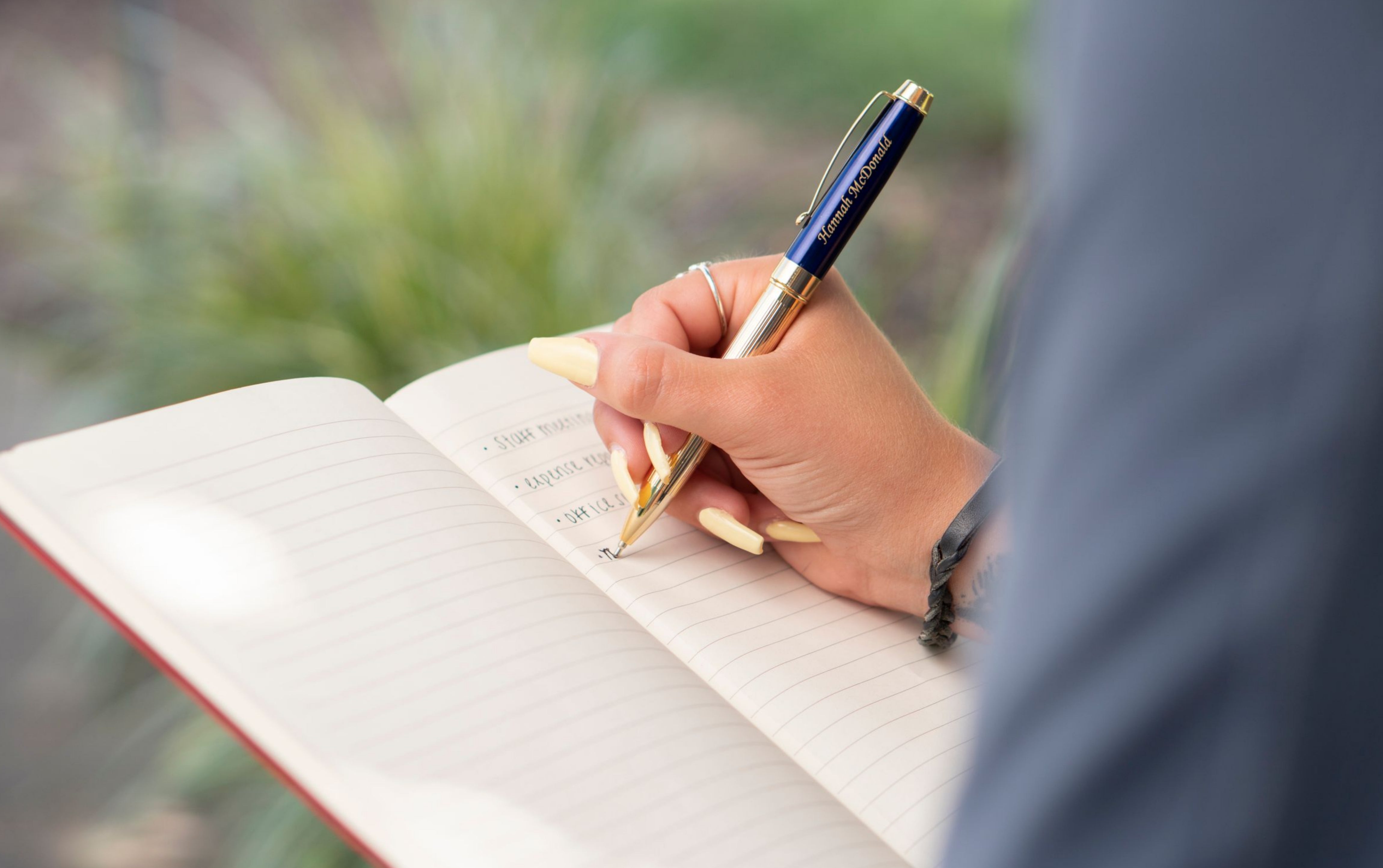 Woman holding engraved Braxton Blue Ballpoint while taking notes