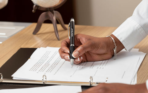 person writing on document using black lumen engraved pen