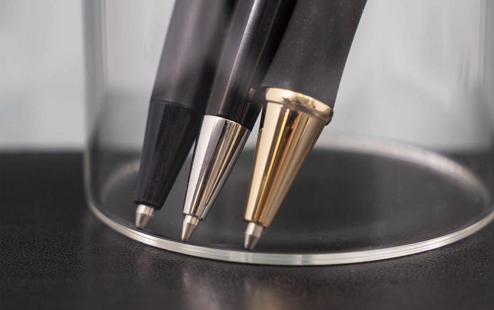 three ballpoints facing down in clear cup