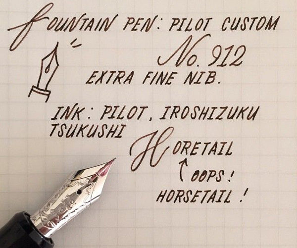 An extra-fine nib pen writing on white paper in black ink