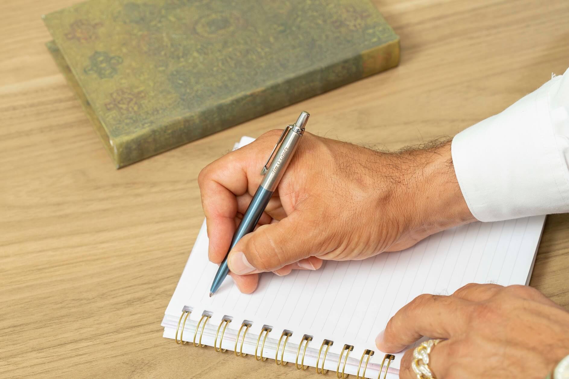 man writes on paper with Parker Jotter Waterloo Blue gel ink pen