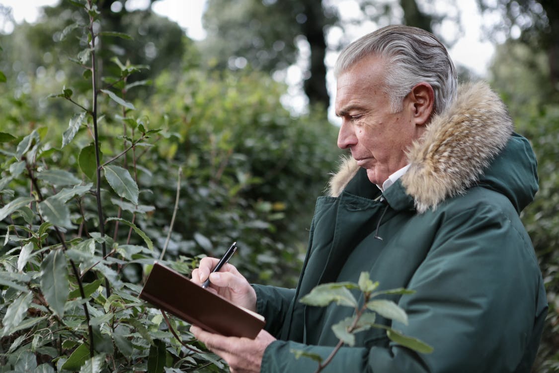 Concentrated senior man writing on notepad