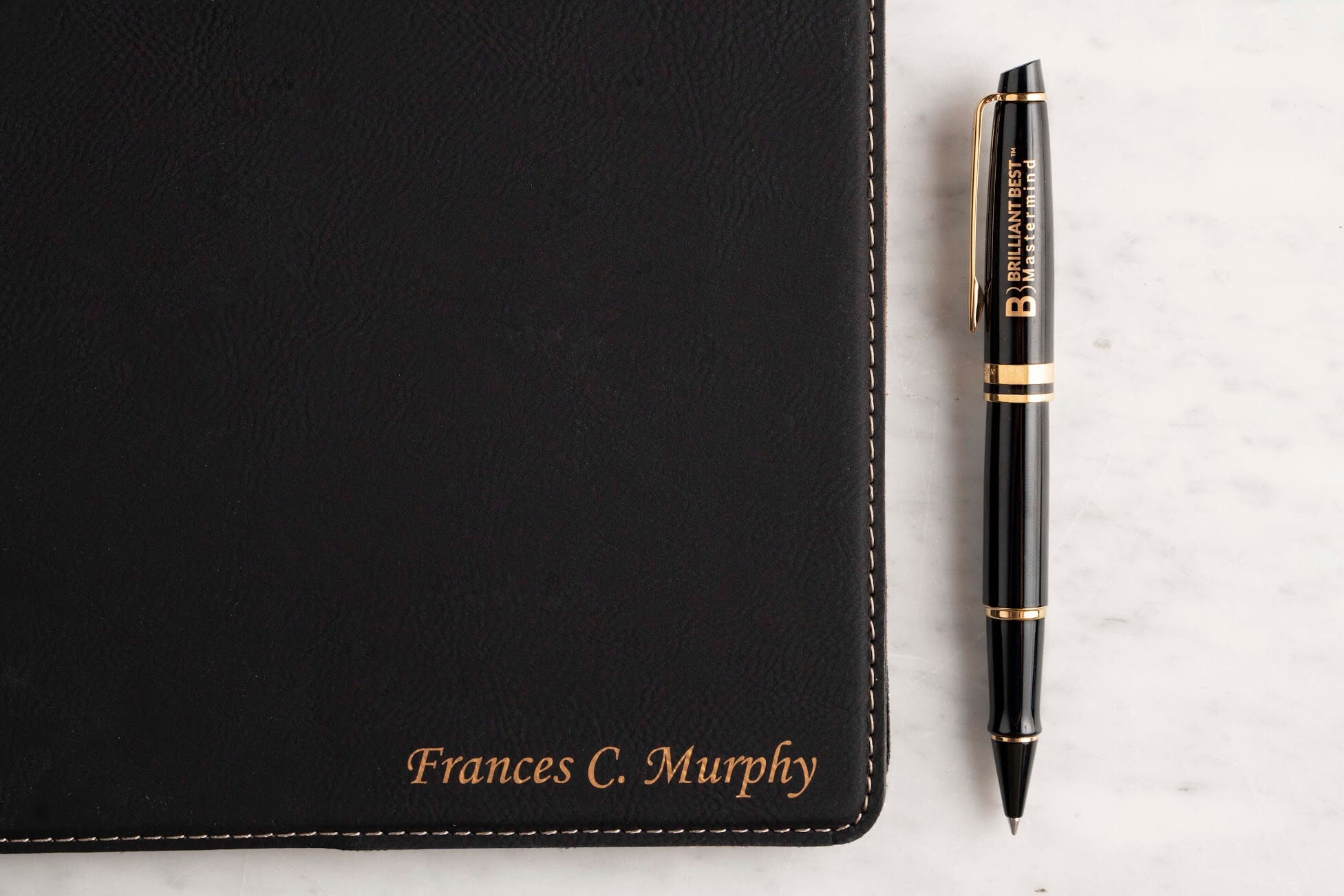 A Dayspring Pens black gift padfolio with gold custom engraving and a Waterman Expert ballpoint pen with logo engraving on the cap