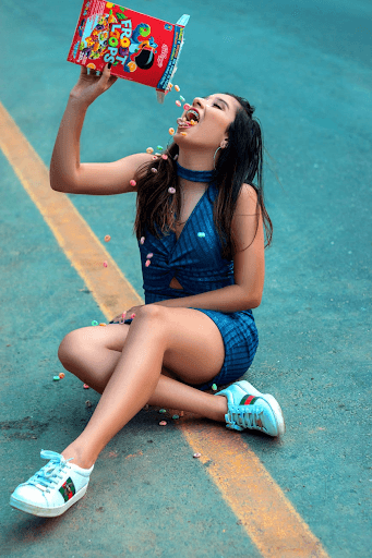 lady sitting on the grass and eating cereal from the box