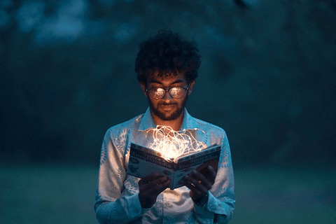 guy reading a book in the dark with fairy lights