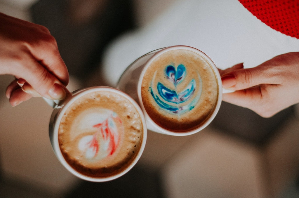 Two cups of colorful fresh cappuccino brews with pink and blue hues