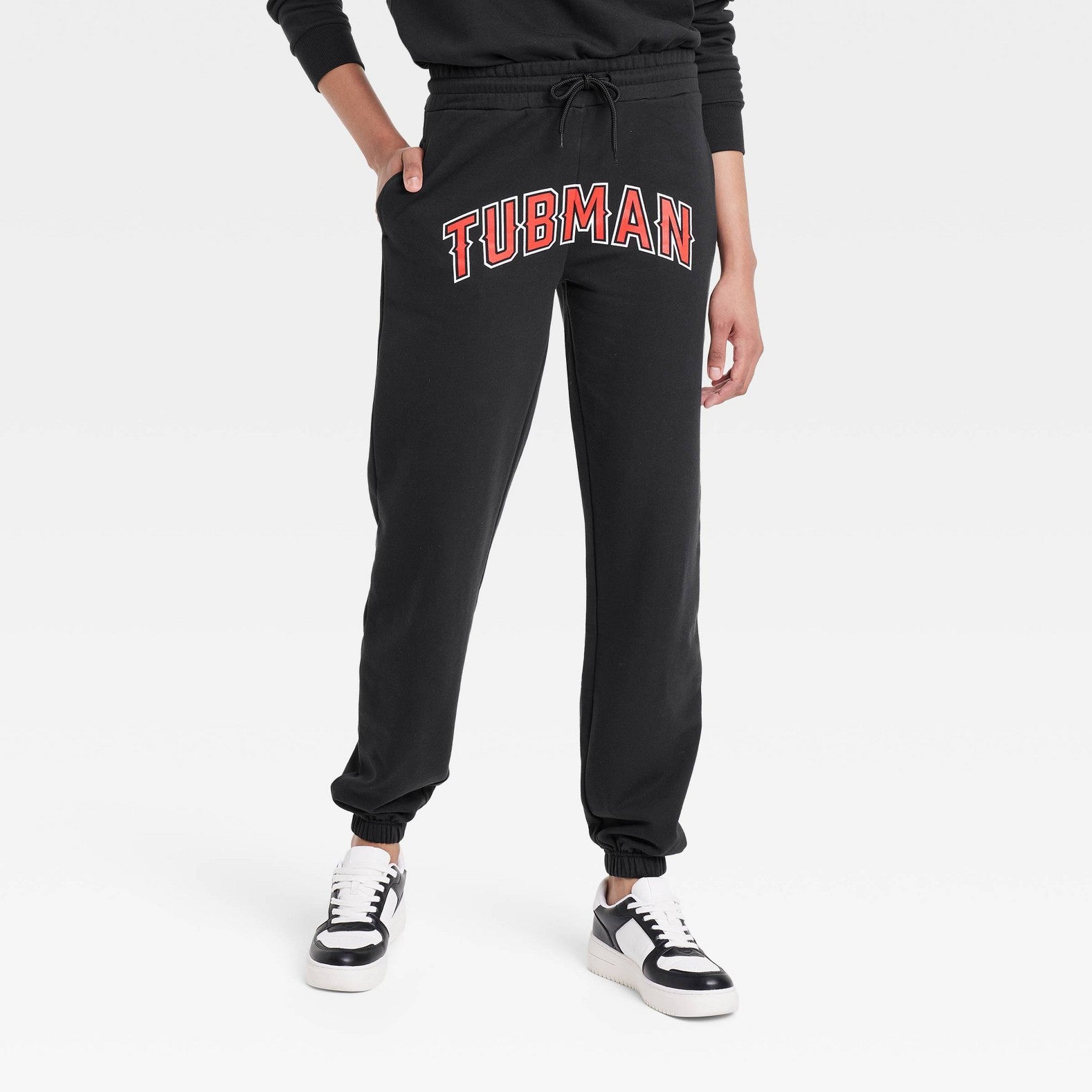 a person's legs, they are wearing black sweatpants that say Tubman