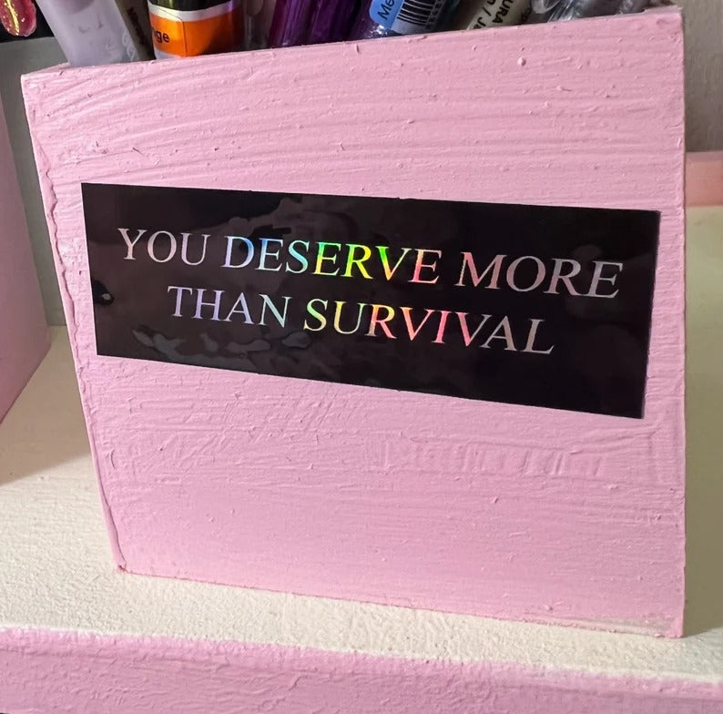 you deserve more than survival holographic sticker on pink box