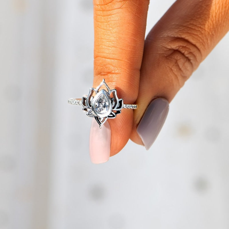 Anel Feminino Flor de Lótus em prata 925 com zircônia, segurado entre os dedos, destacando seu brilho e detalhes sofisticados.