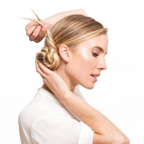 Blonde model doing her hair by wrapping her ponytail around a bun using Easy Updo Extensions