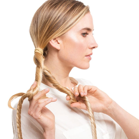 Model separating hair into 2 sections using Easy Updo extensions with white background doing her hair