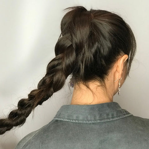 Woman holding long hair braid in her hand in army green shirt using Easy Updo Extensions