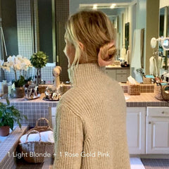 Woman in grey sweater standing in bathroom with updo bun in pink on her fine, thin, and short hair