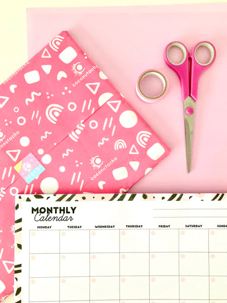 custom pink branded tissue paper with a pink, black and white monthly desk calendar and a pair of pink scissors