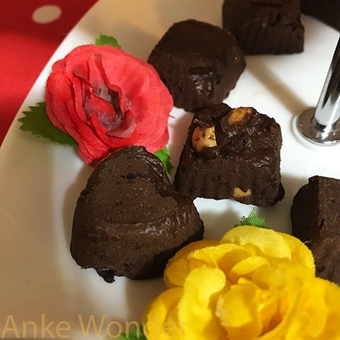 Chocolate Pralines with flower decoration on a white porcelain plate.