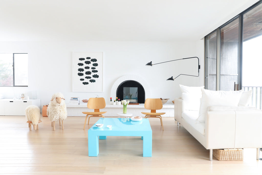 Modern, minimalist living room with blue coffee table, sheep, artwork, wood floors in Faunamade blog post