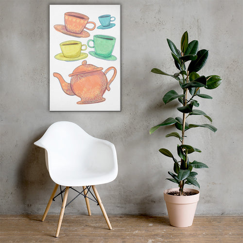A white canvas with artwork on it hanging above a white chair with a potted plant to the side. The wall is light gray.The artwork is on a white background with four teacups on saucers and one large teapot. The teacups are in muted colors of orange, blue, yellow and green and the teapot is a muted orange. On the teacups, saucers and teapot there is a light flower detail pattern.