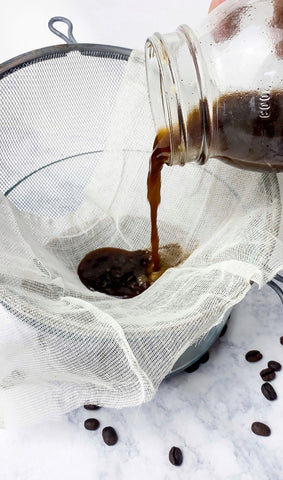 Pouring cold brew coffee from a jar through a strainer.