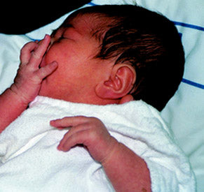 Before a feed: a stirring baby, with its fingers in its mouth.