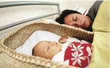 Image showing mother asleep in bed with her baby. The baby is in his own bed beside her.