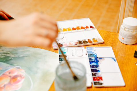 young female artist washing and cleaning paintbrushes in water before painting