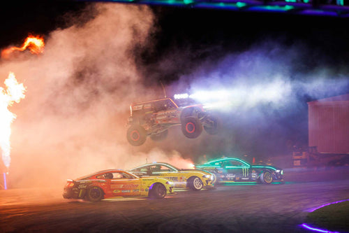 Loren Healy jumping the track in his Ultra4 Bronco while Chelsea Denofa and Vaughn Gittin Jr, and Adam LZ drift underneath him in their Mustang RTR Spec 5-Ds.