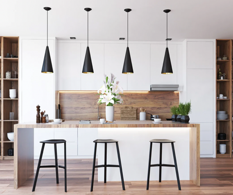White minimalist kitchen with wooden shelving and an island, three black bar stools positioned to the front and four black pendants hang over the island