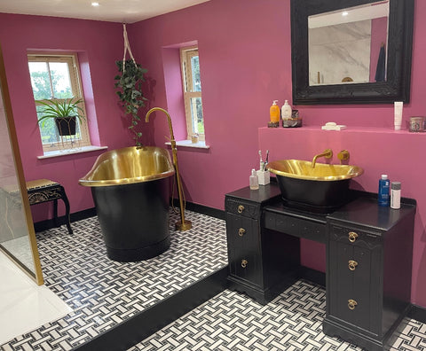 Pink bathroom, with black and gold free standing bath and black dressing table upcycled in to a vanity which a black and gold sink sits upon