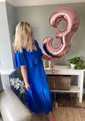 Celebrating SFS third birthday in a blue dress with pink balloon