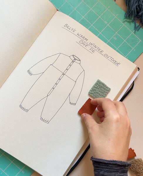 Photograph of sketchbook showing process drawing of baby boy's fleece onesie design