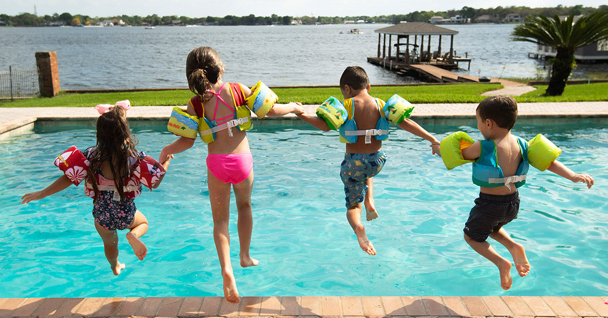 4 kids jumping into pool with Body Glove Paddle Pals Life Vests