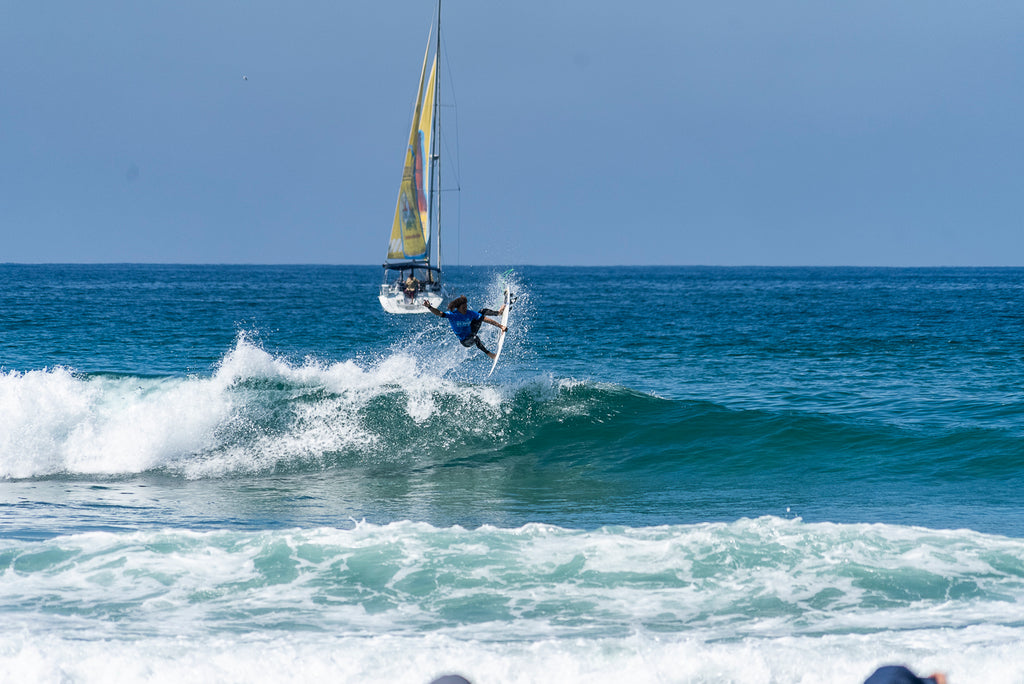 Nolan Rapoza surfing in the air with a sailboat in the background